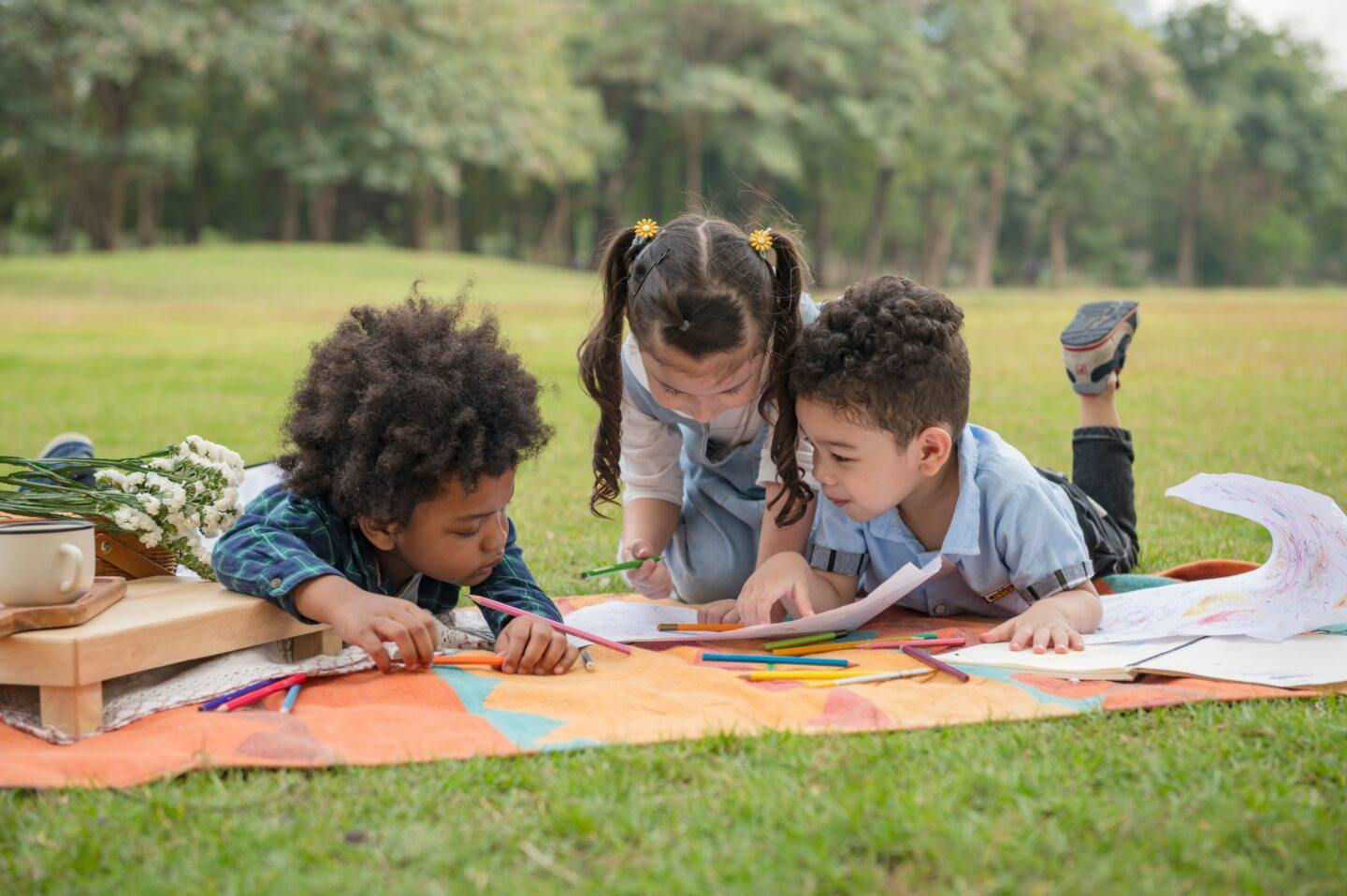 three kids playing in grass outside making art