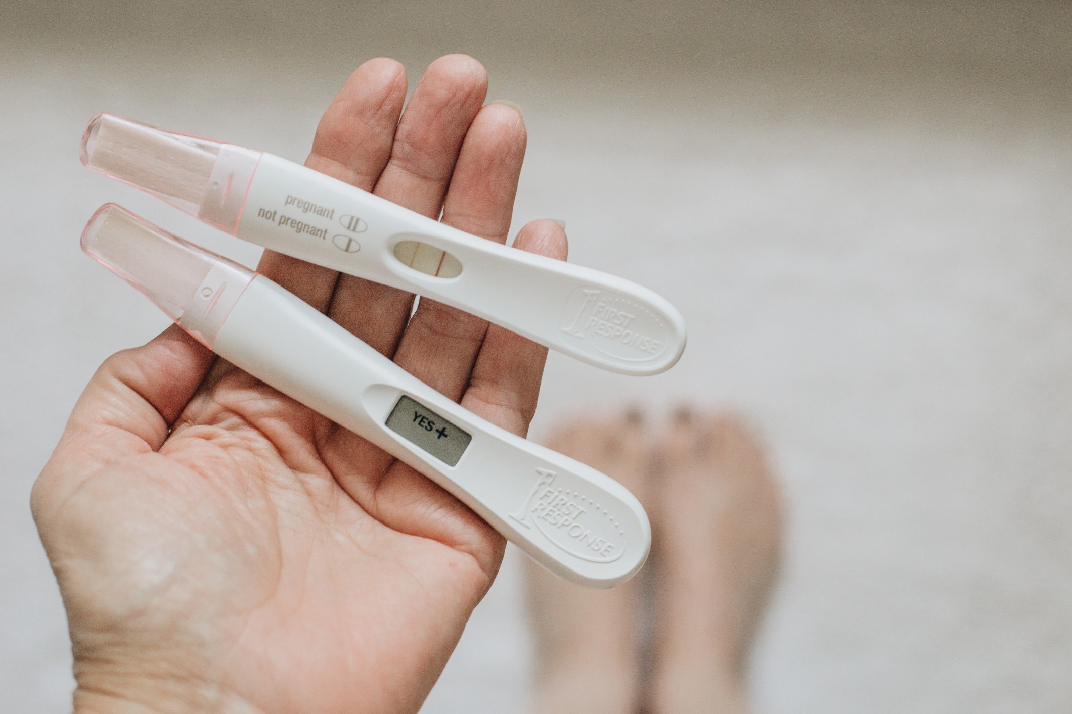 two positive pregnancy tests in hand looking down women s health life baby family expecting first t20 eobb2a 1 Motherly