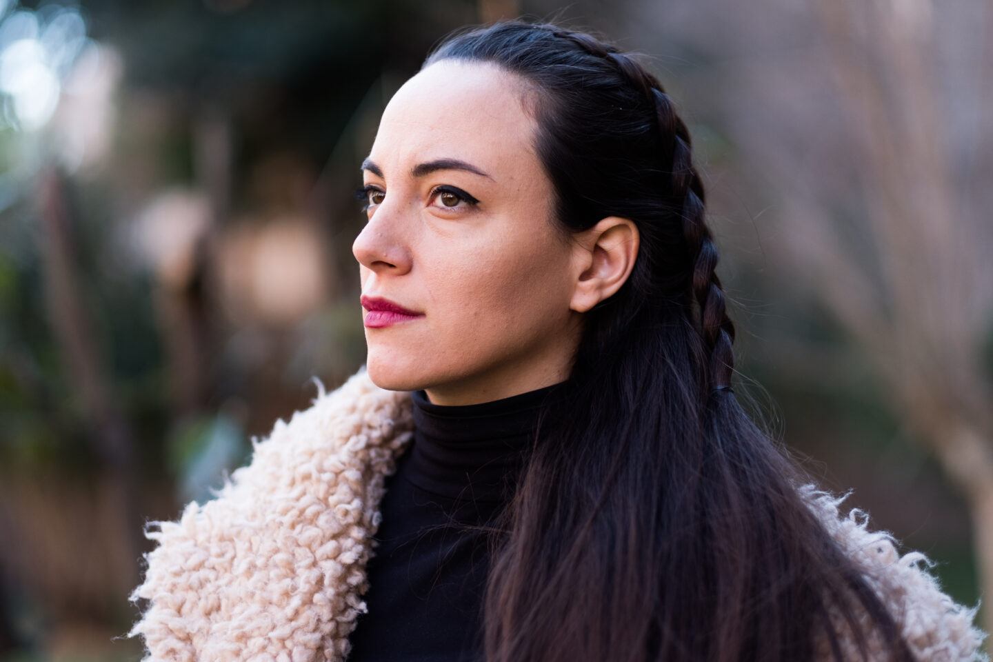 thoughtful woman with dark hair and furry jacket looking away