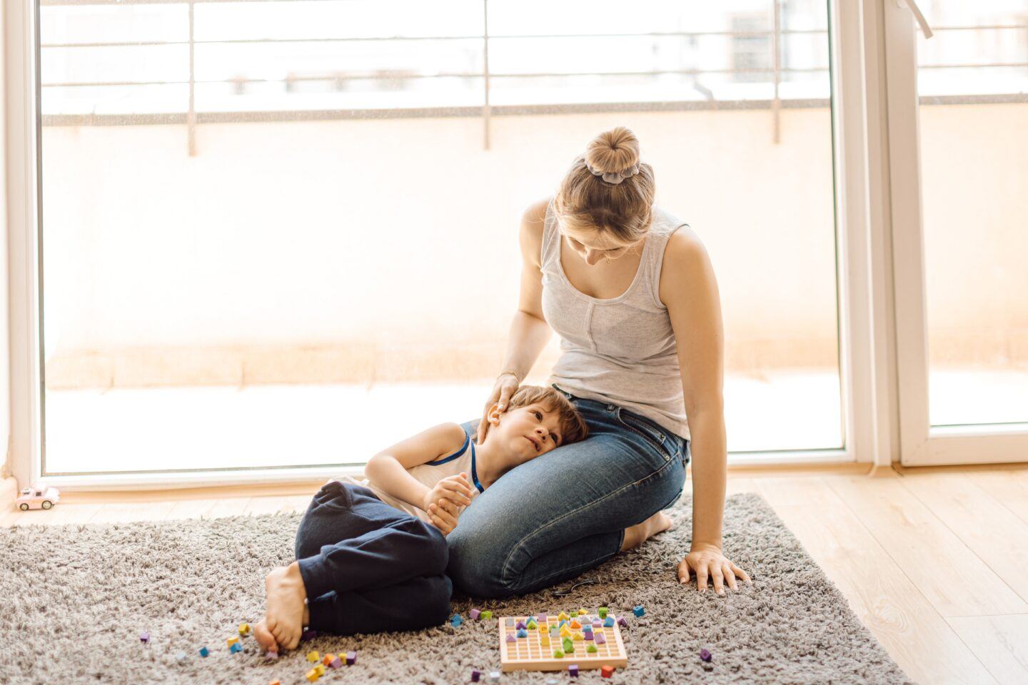mother sitting with child's head in lap with discarded puzzle pieces on the floor