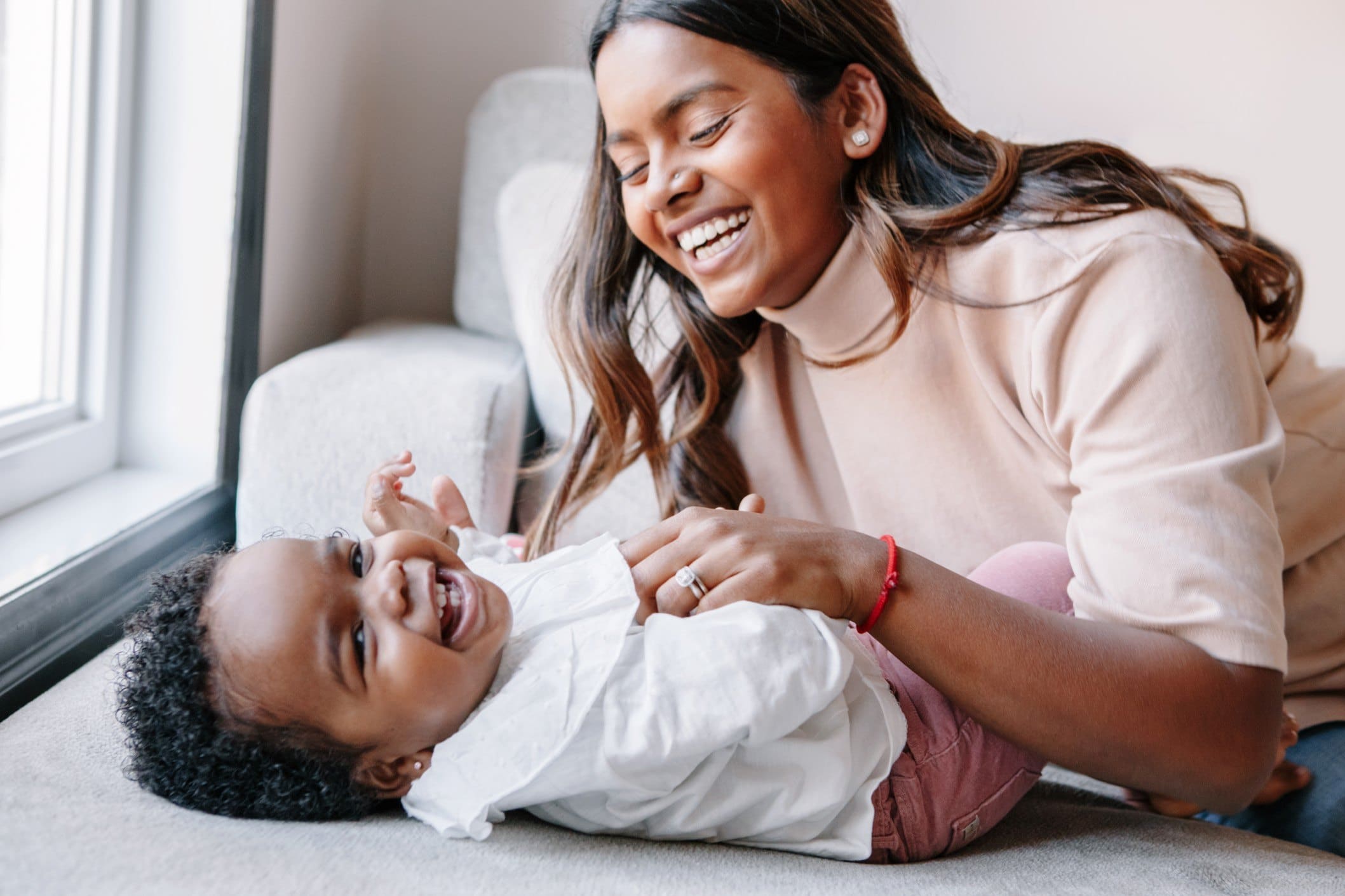 indian race young smiling mother playing with black african curly toddler baby girl candid authentic t20 ZYWoPY