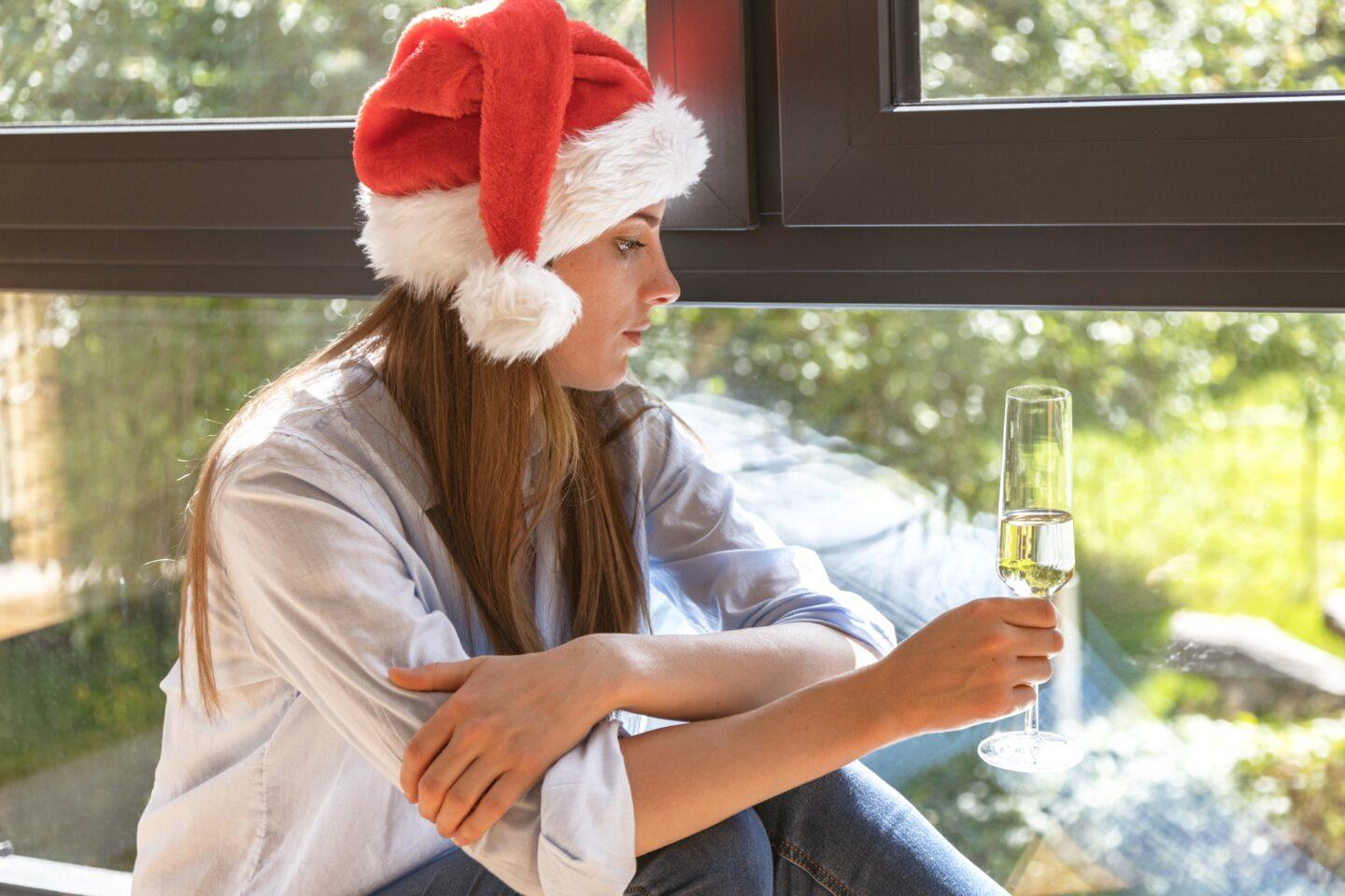 woman in santa hat drinking looking sad