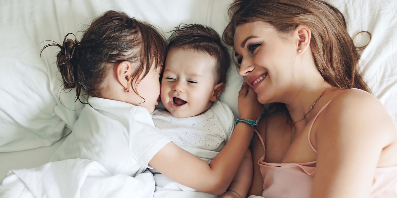 smiling mom in bed with two kids- new year's resolution list