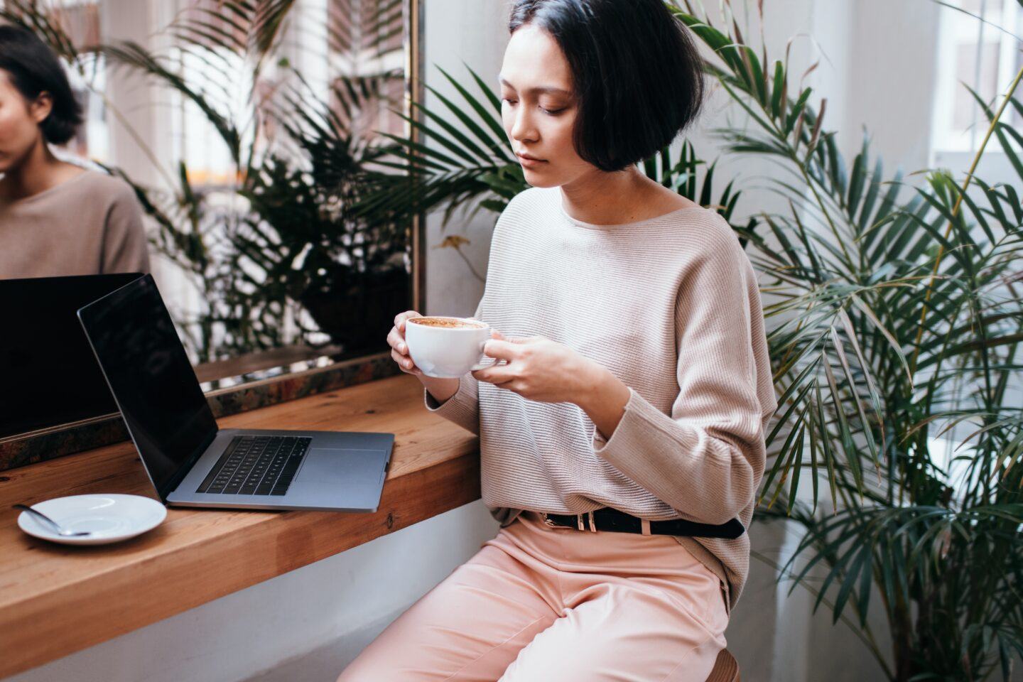 woman drinking coffee at a cafe with laptop