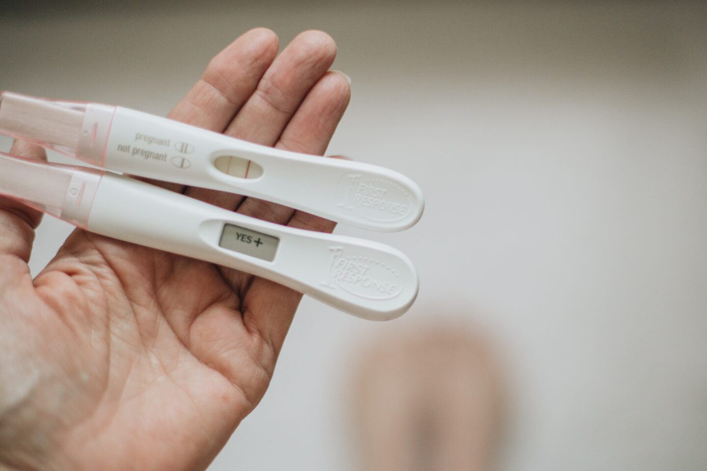 woman holding two positive pregnancy tests in open palm