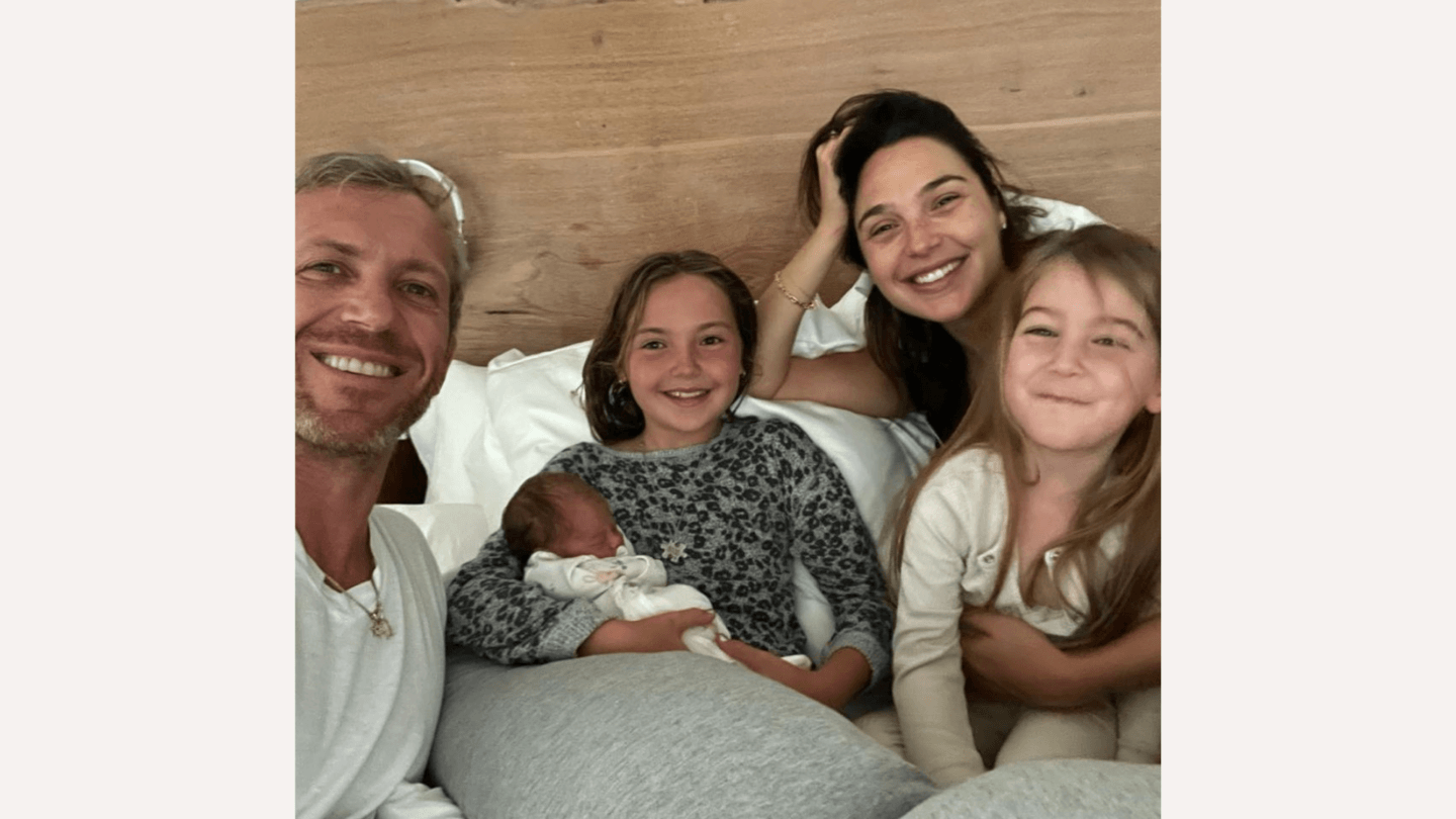 Gal Gadot lying with her family and newborn baby