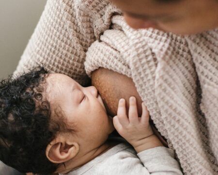 Black mother breastfeeding infant son Motherly