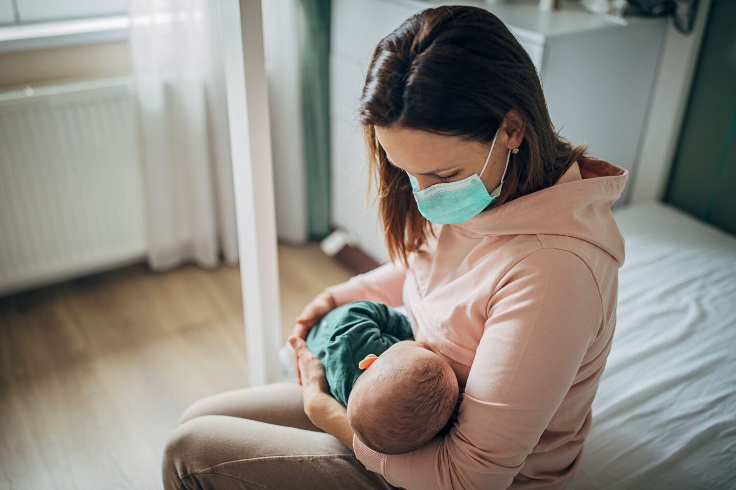 Safe to breastfeed with Covid: Mother wearing face mask and breastfeeding baby at home