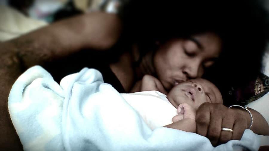 mom kissing baby while breastfeeding