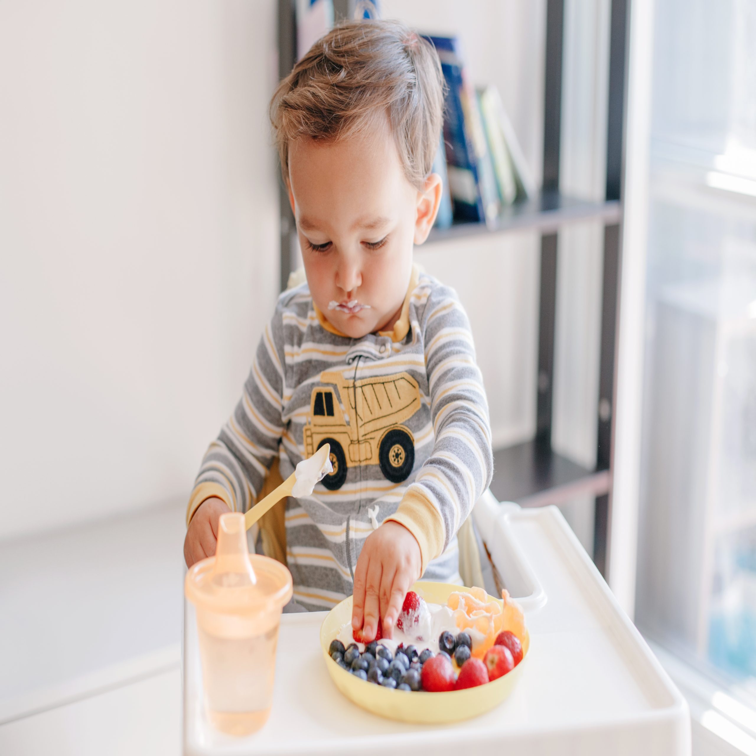 playing with food - baby eats yogurt and blueberries in high chair