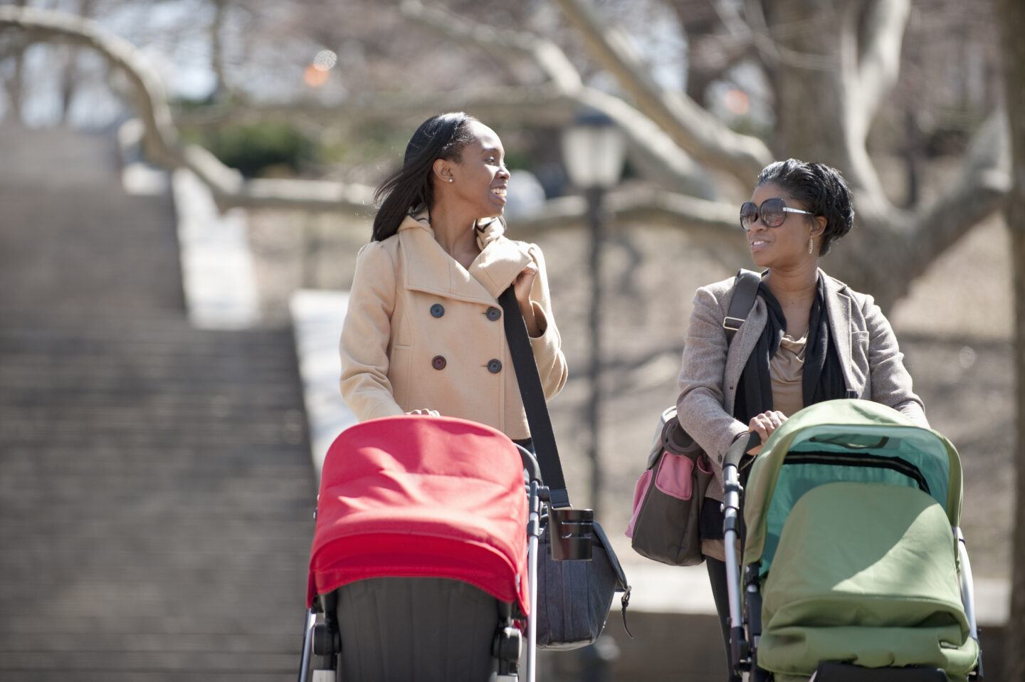 empathy in motherhood: Two moms pushing babies in strollers in the park