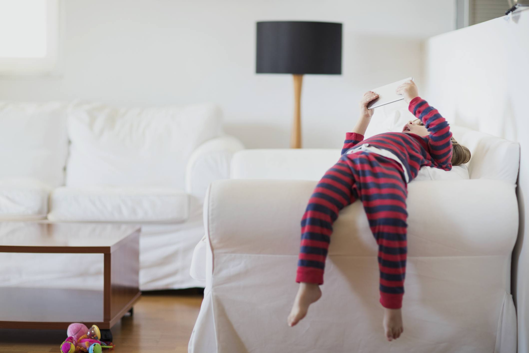 screen time: toddler using tablet while lying on couch