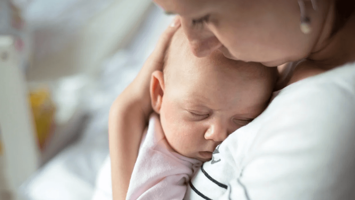 mom snuggling sleeping baby under her chin