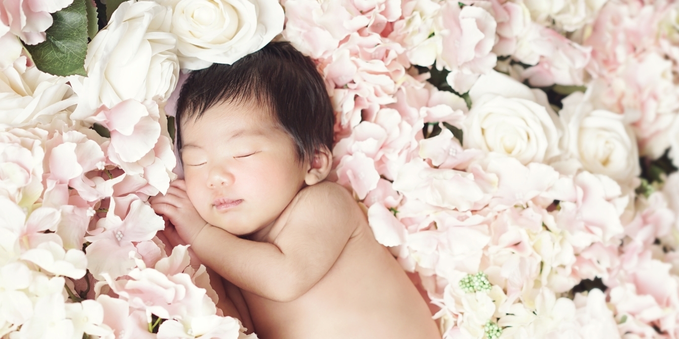 little baby asleep on a bed of flowers- march baby names