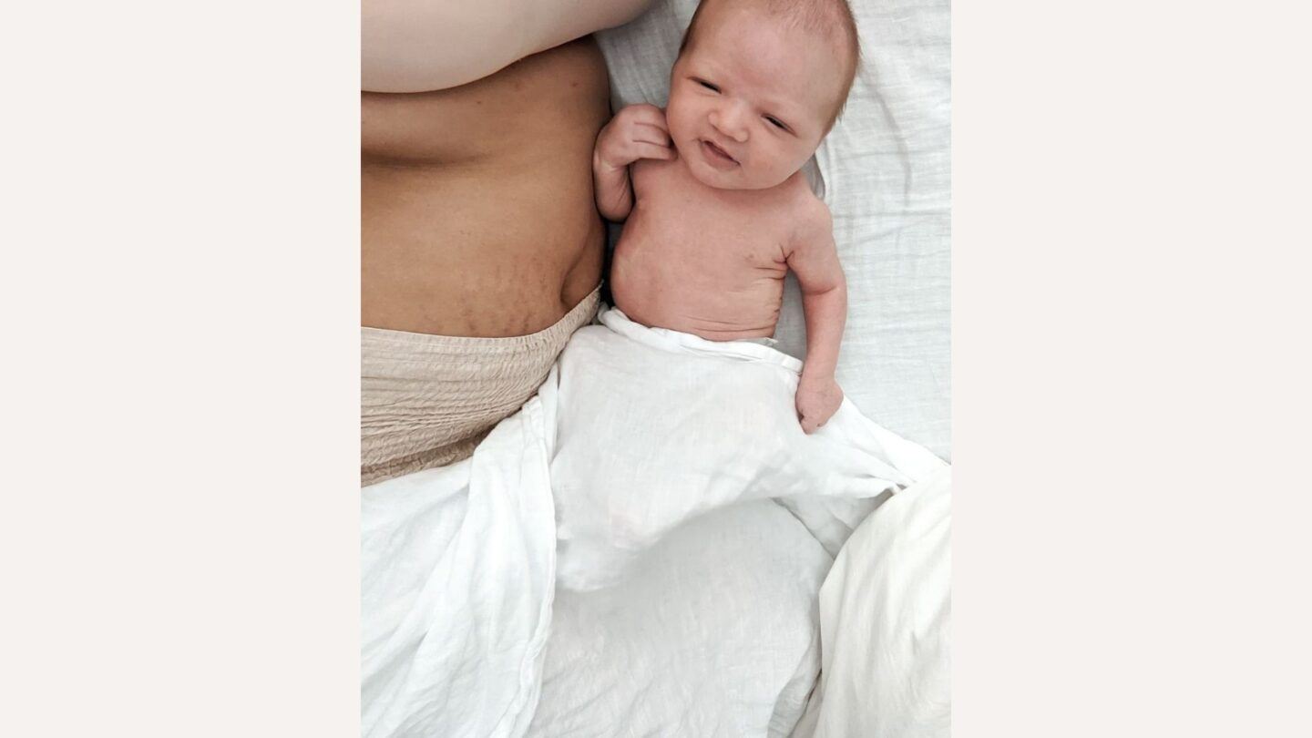 Upclose of baby laying by woman's postpartum stomach