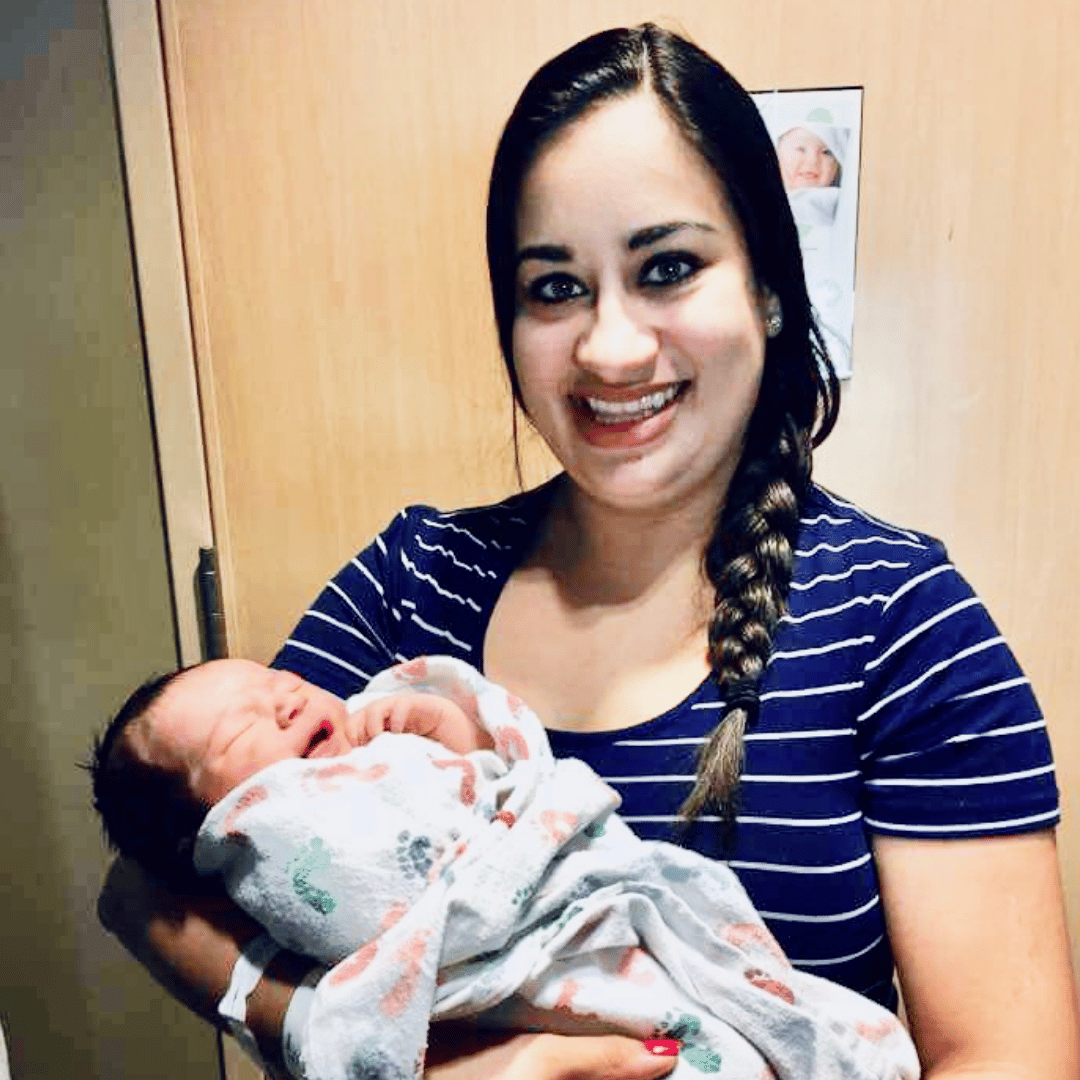 mom smiling for a picture holding a newborn in the hospital - essay on therapy for postpartum depression