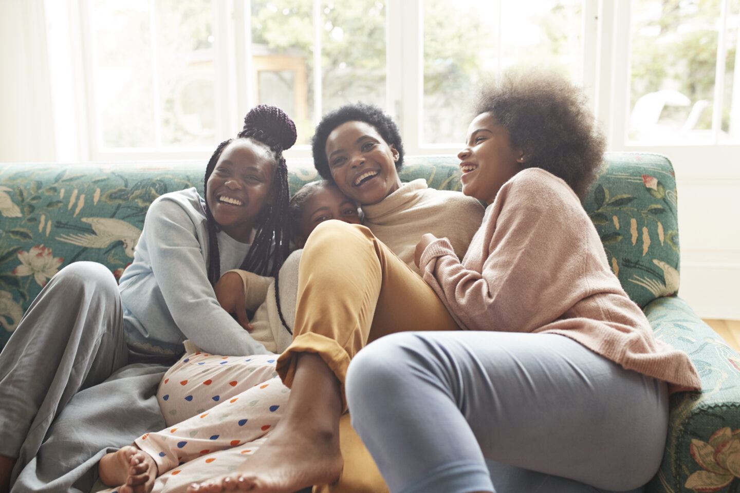 Portrait of happy woman embracing girls at home- mothering