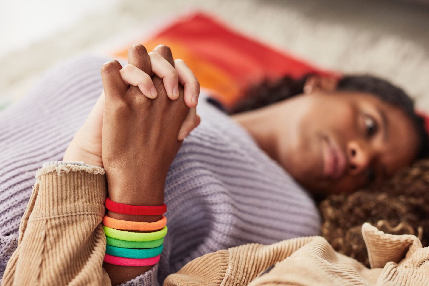 queer miscarriage: Couple holding hands laying on floor together