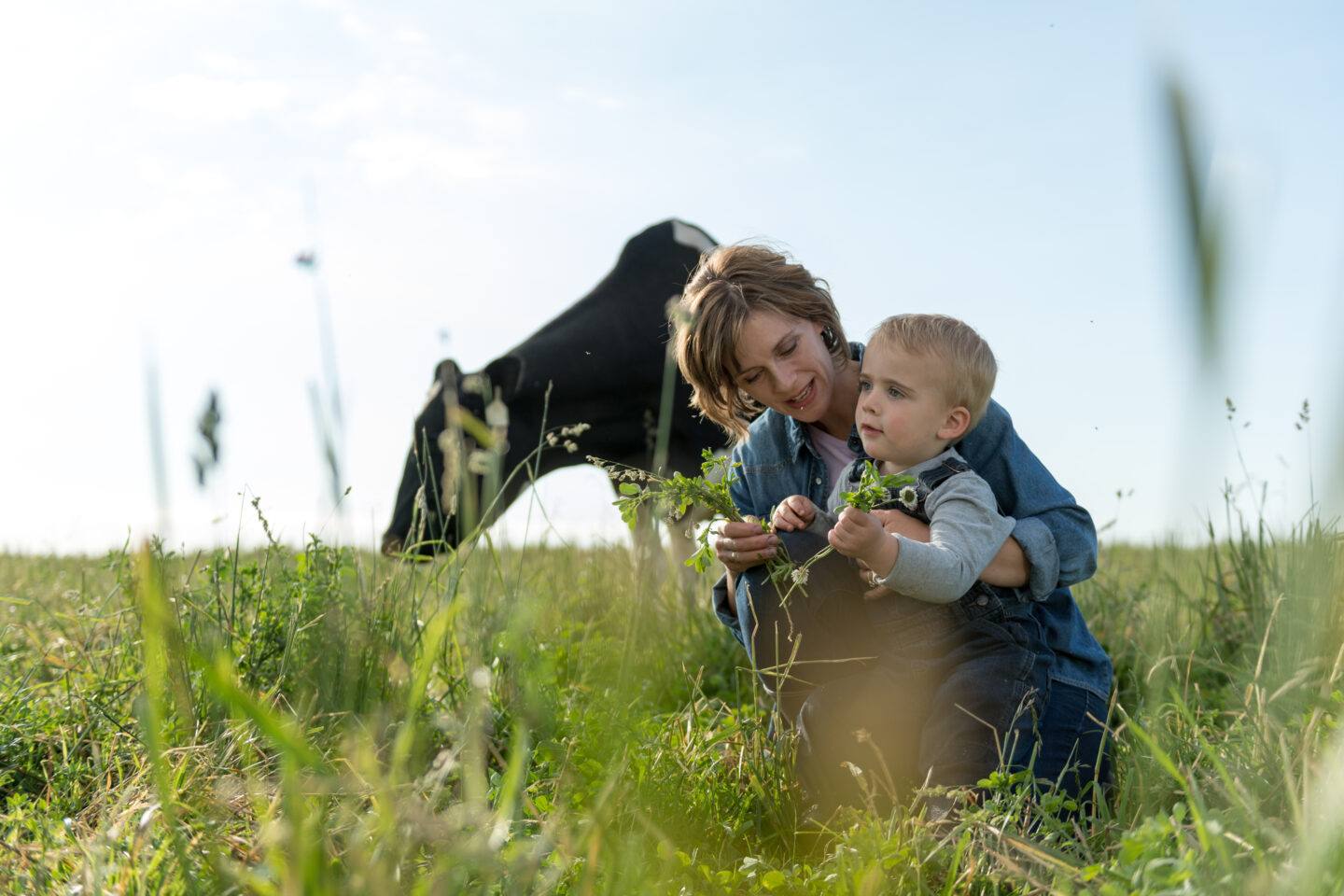 mom and son in a field with a horse behind them