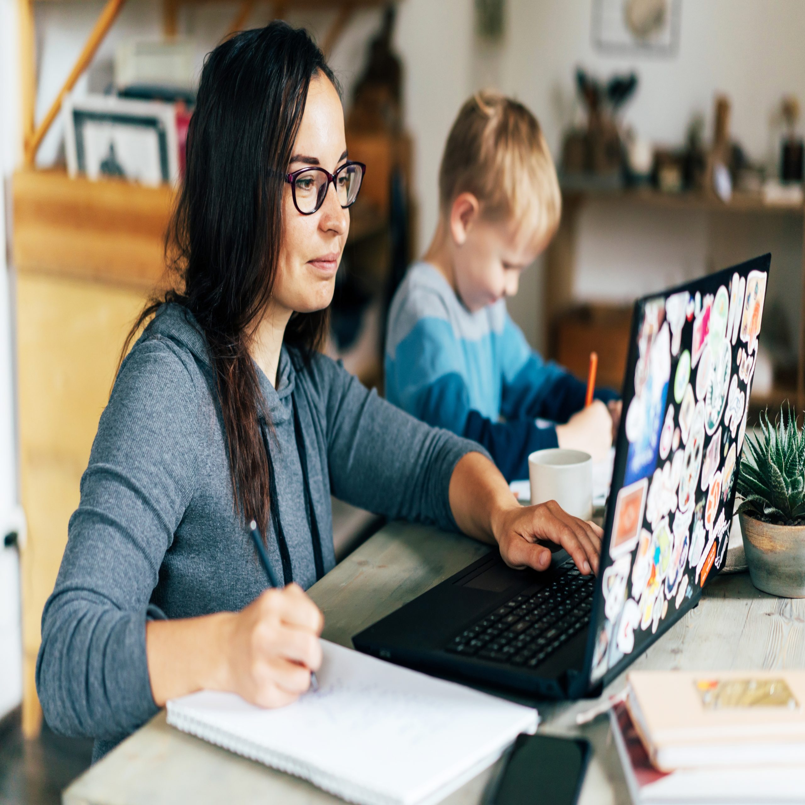 working mom: mom on laptop with son sitting by her working on homework