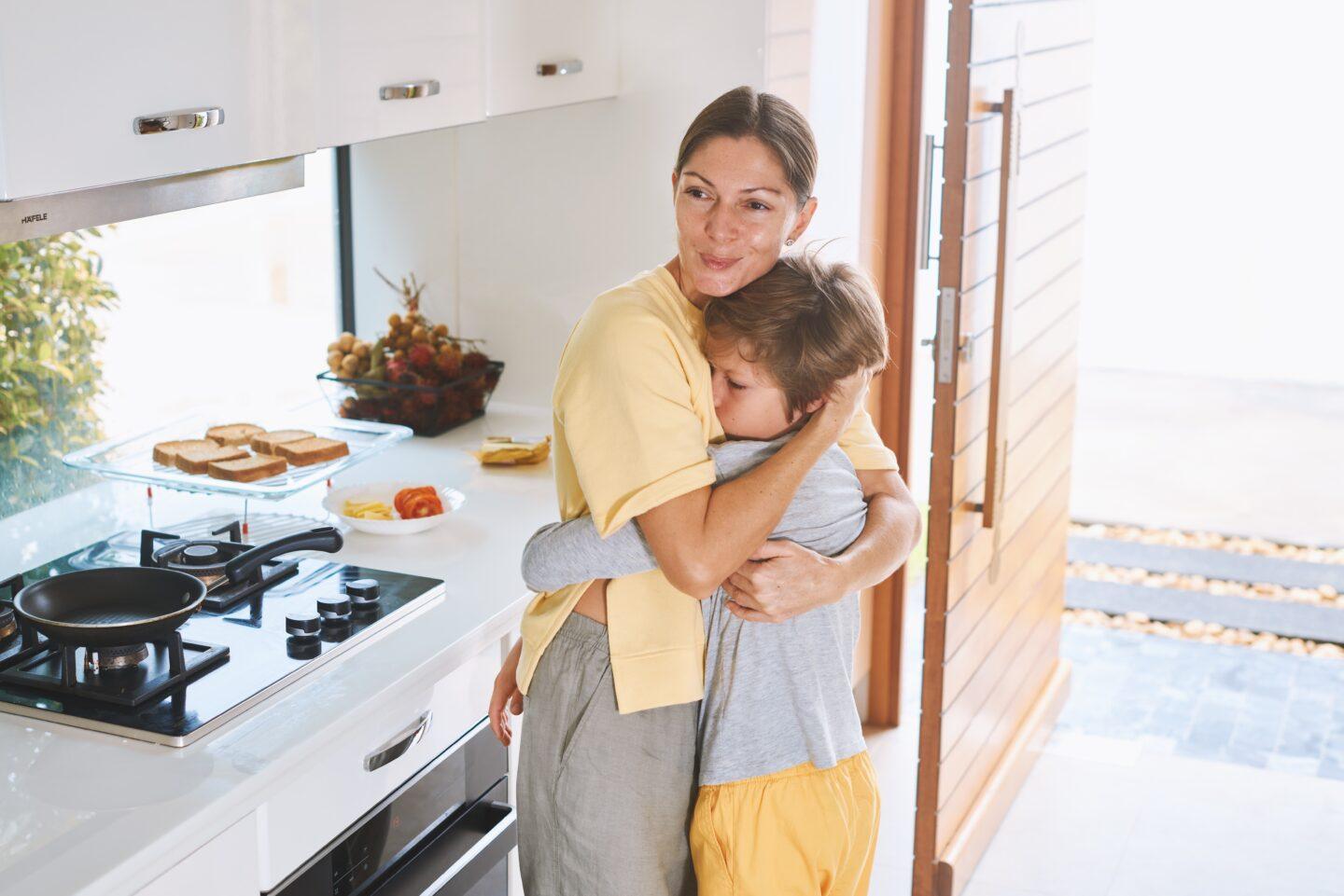 ocd in children: mom and son hugging in kitchen at breakfast