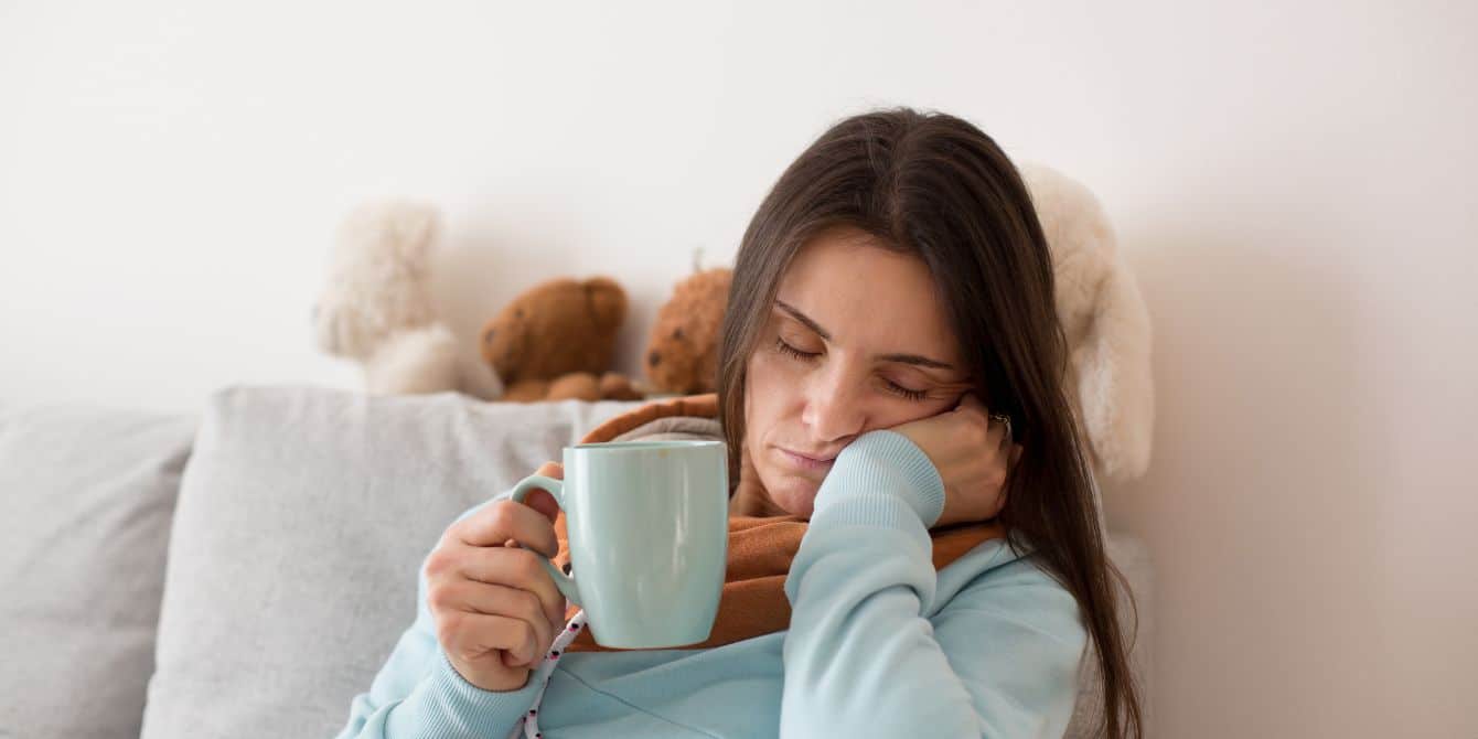 tired mom falling asleep while holding coffee cup- daylight saving time