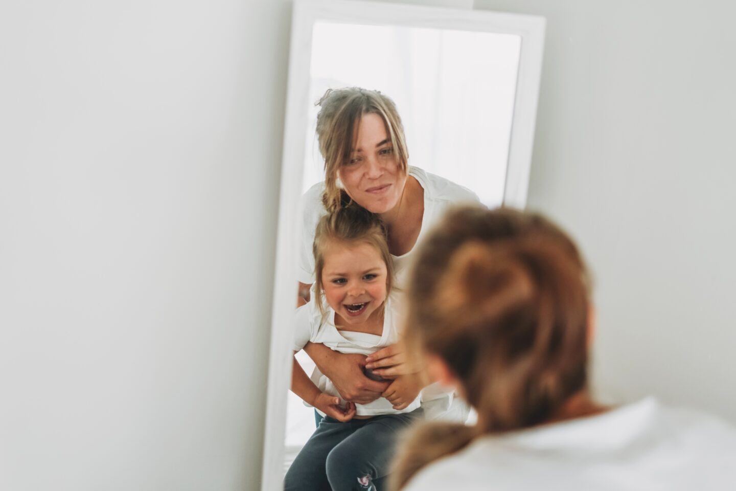 Stay-at-home mom: young mom and daughter looking in mirror