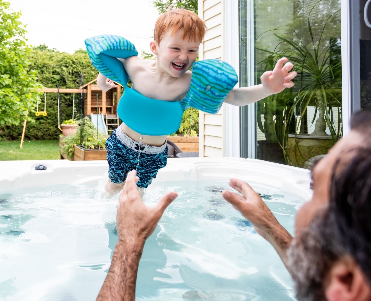 toddler boy wearing puddle jumpers in pool hot tub