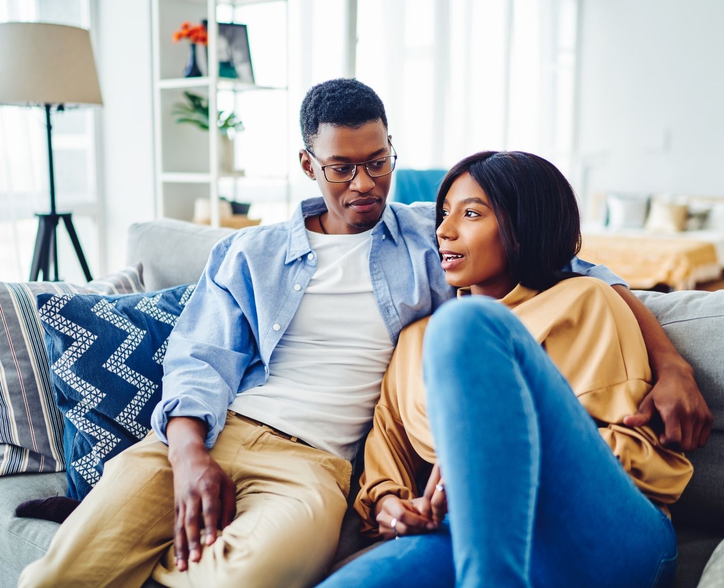 infertility: couple sitting on couch at home talking - stop calling infertility a women's health issue