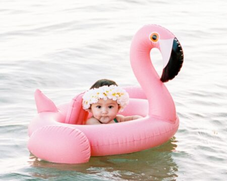 baby wearing flower crown floating in intertube in ocean Motherly