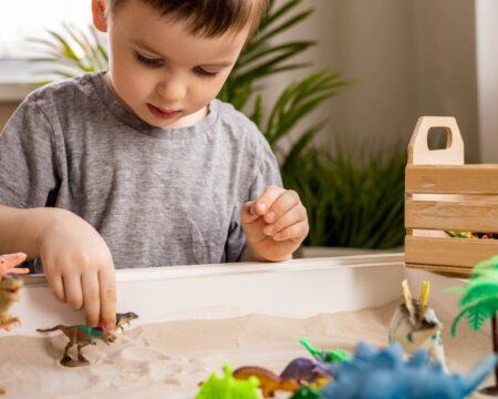 cute baby boy playing sensory box dinosaur world kinetic sand table with carnivorous and herbivorous t20 PJRw48