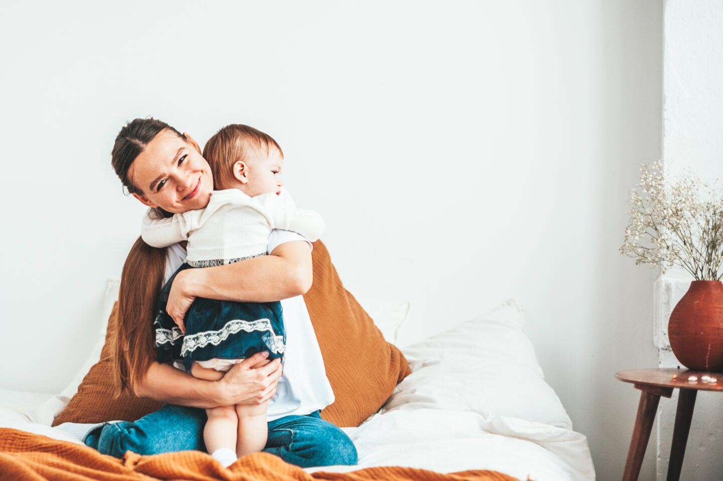 mother hugging baby sitting in bed - advanced maternal age