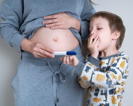pregnant woman shows her young son a positive pregnancy test concept of happy family t20 7y8xy6 Motherly