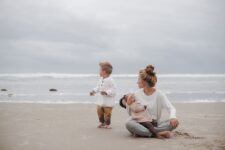 real motherhood moment of mom bottle feeding adopted baby girl sitting on the ground with her toddler t20 A9wPgm Motherly