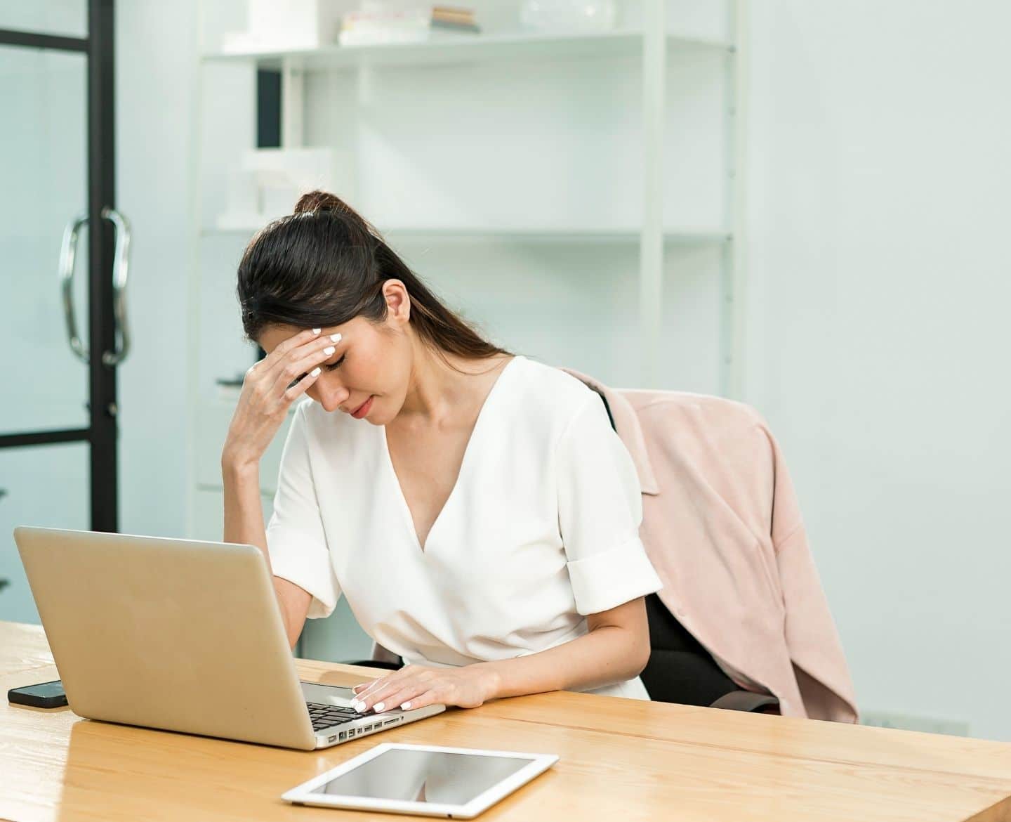 stressed woman sitting at desk with laptop open