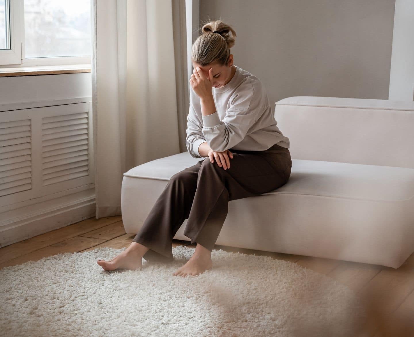 stressed female sitting on couch with her head in her hand