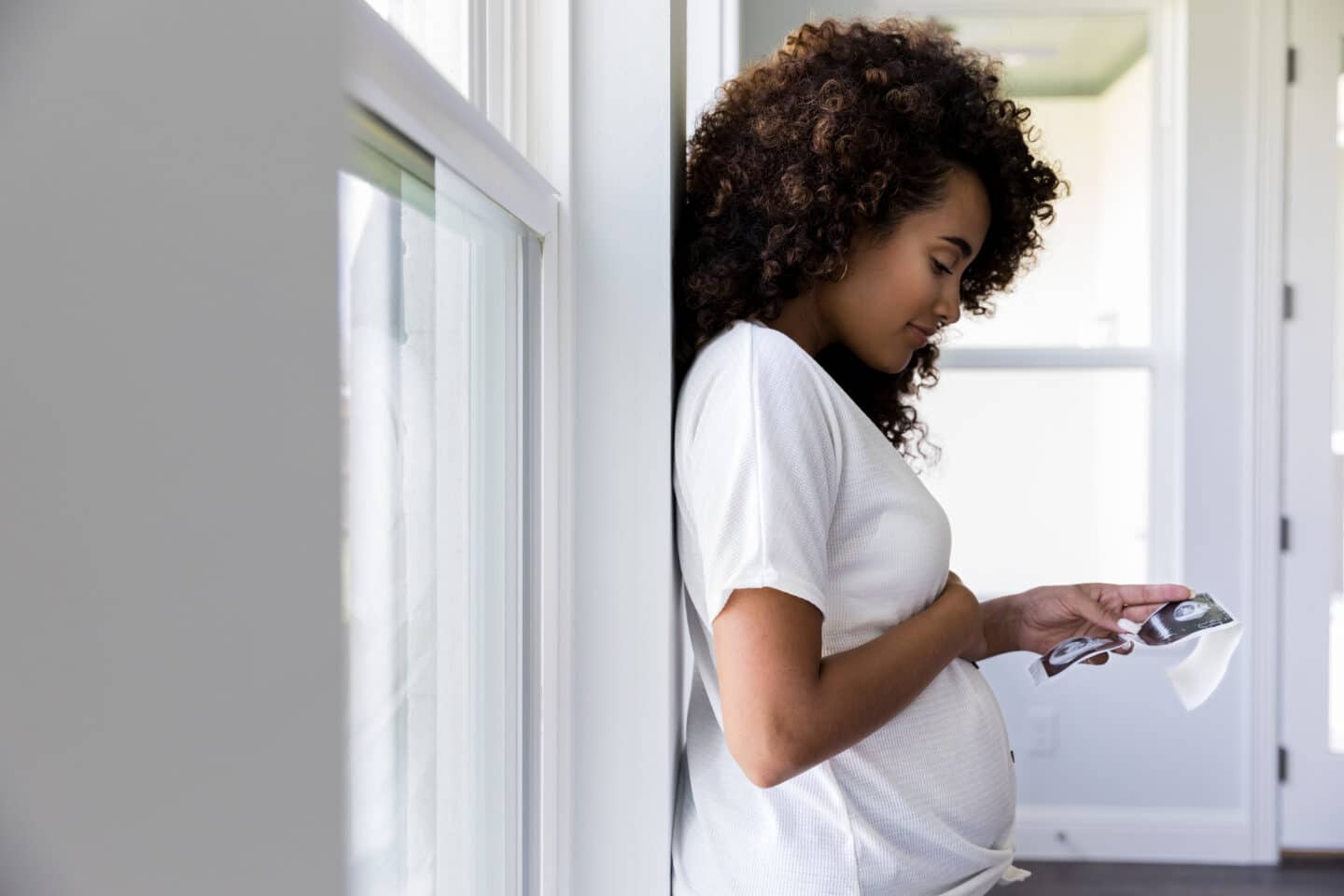 Profile view of pregnant woman looking at ultrasound photos