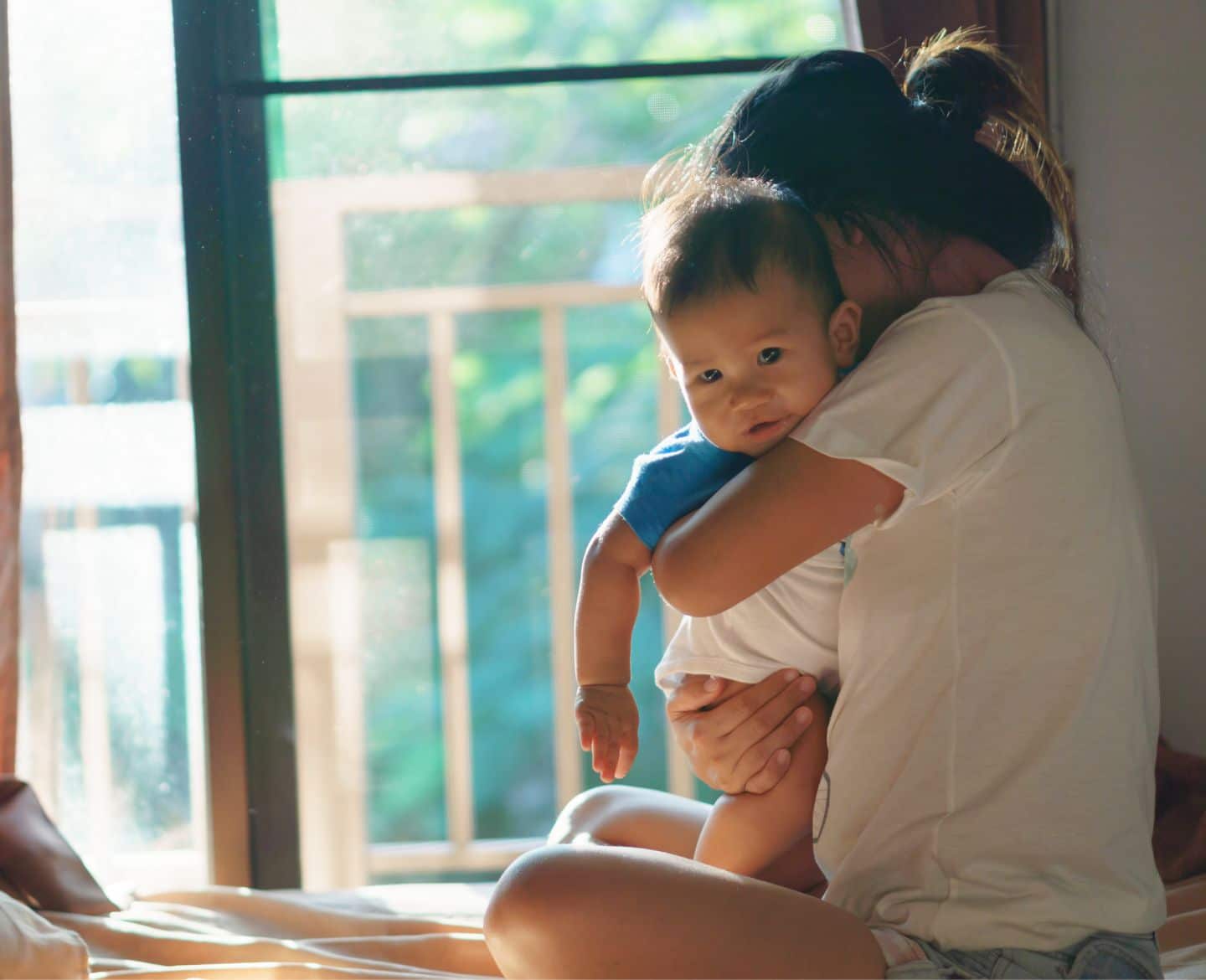 lonely: mom holding baby while sitting on bed