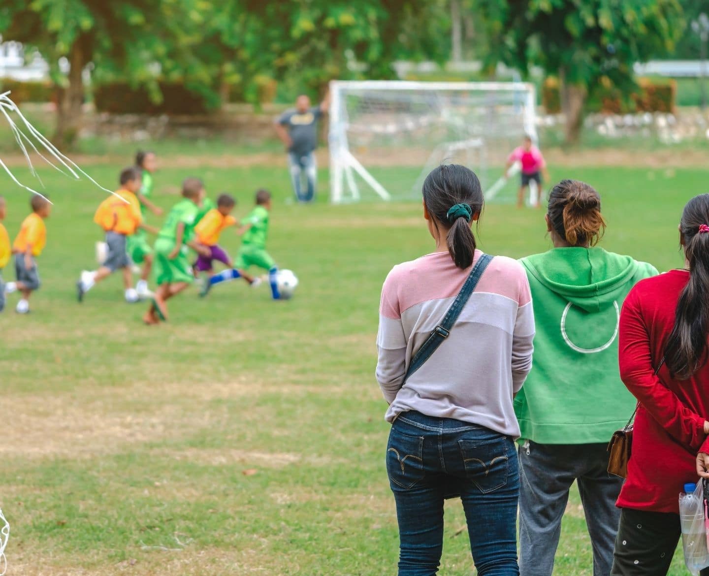 youth sports: group of moms watching kids play soccer