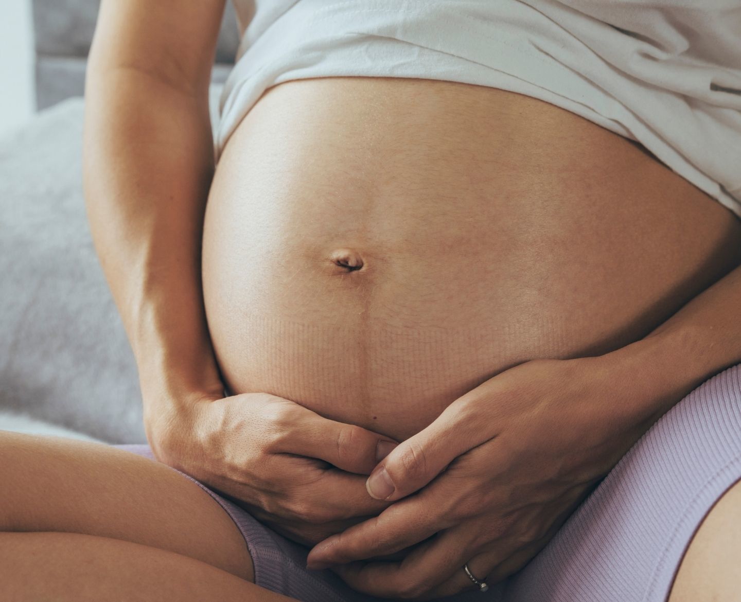 pregnant woman seated and holding bare belly - how to get pregnant