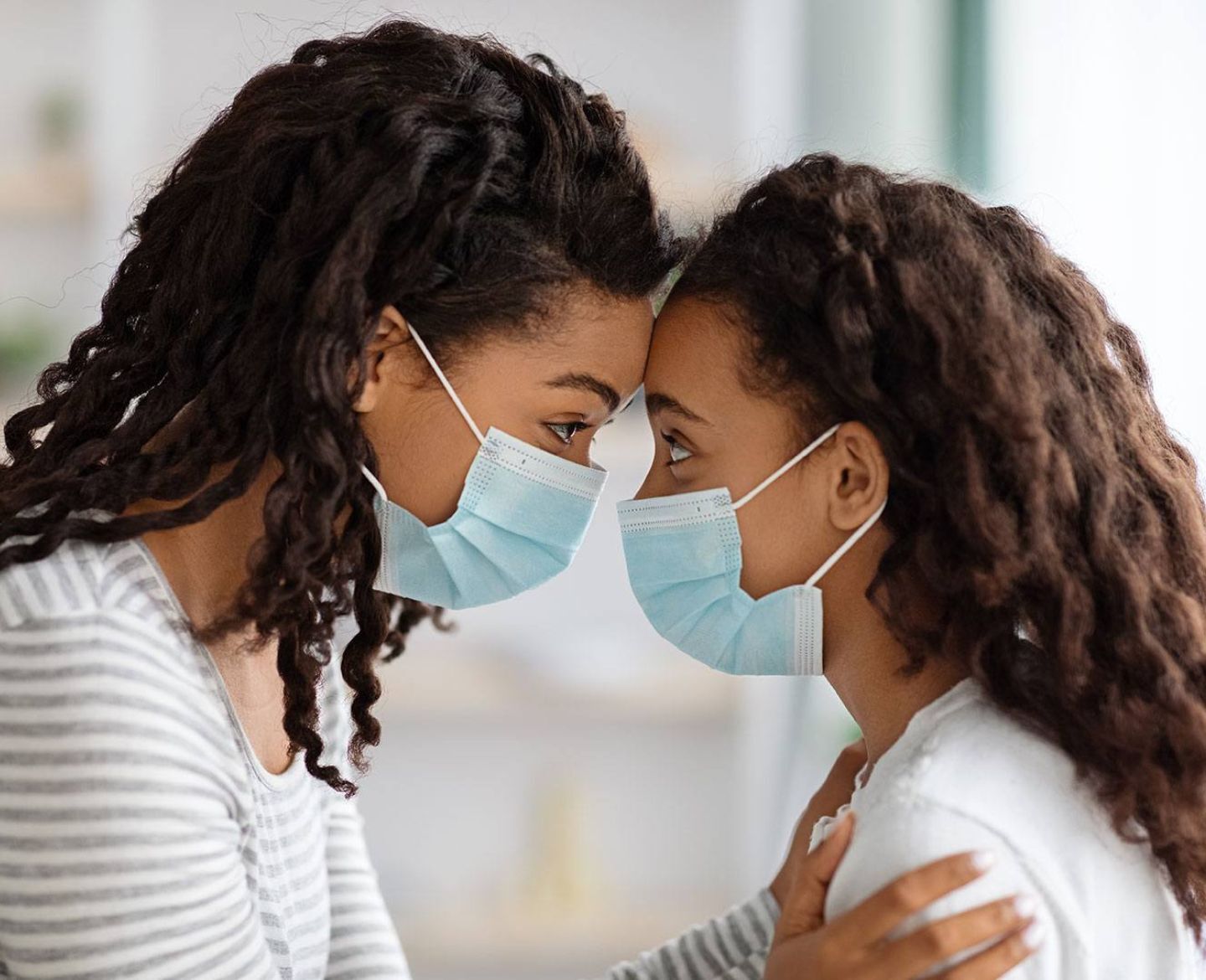 mom and daughter looking eye to eye while wearing masks