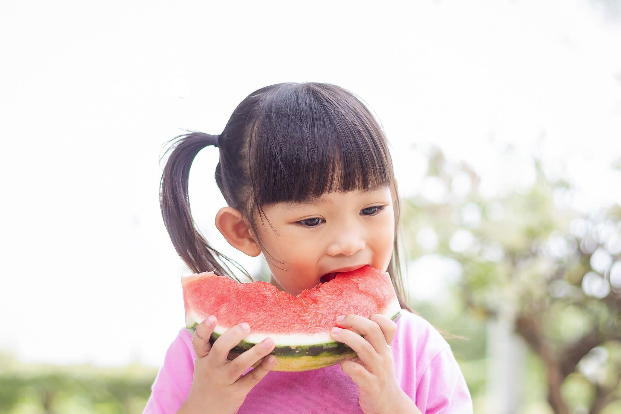 Asian girl eating a piece of watermelon