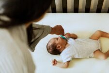 baby sleeping in crib mom offering pacifier1 Motherly