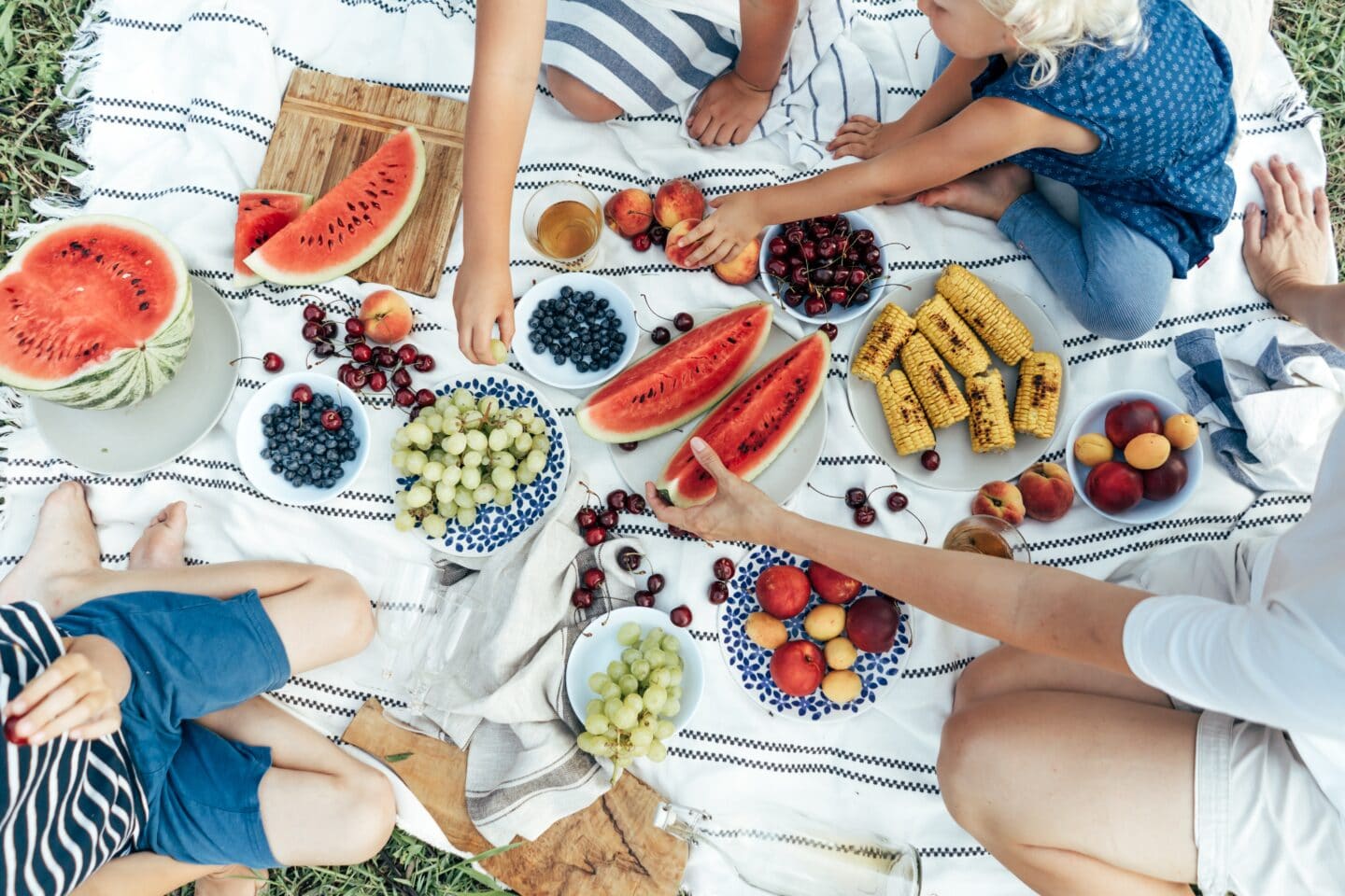 people eating a picnic on a blanket