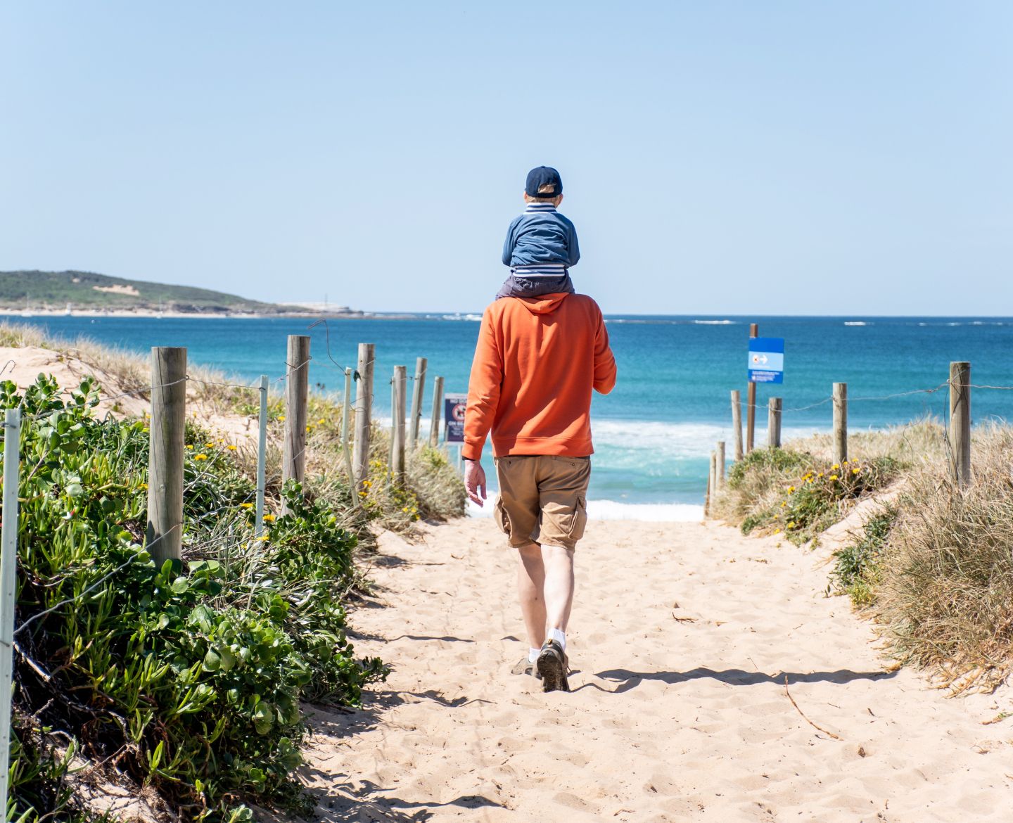 father walking on beach with son on his shoulders