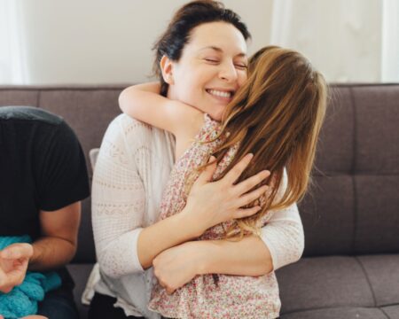 mother smiling hugging daughter dad holding newborn Motherly