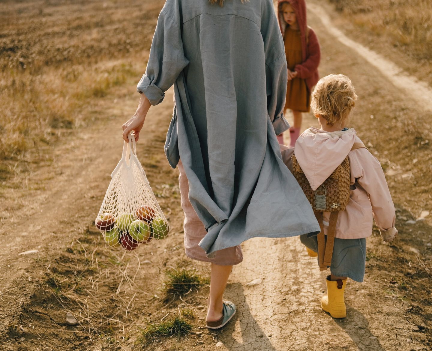 mother walking on dirt road with two children