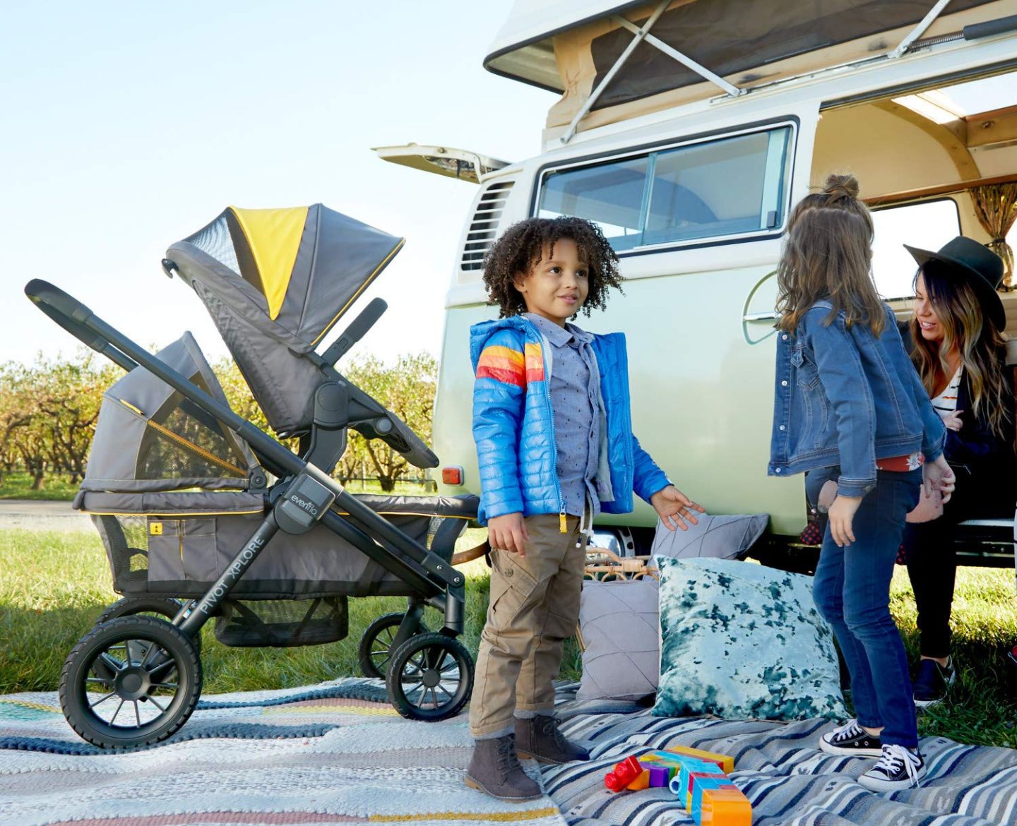 kids standing next to a stroller wagon and camping van - Evenflo Pivot Xplore Wagon