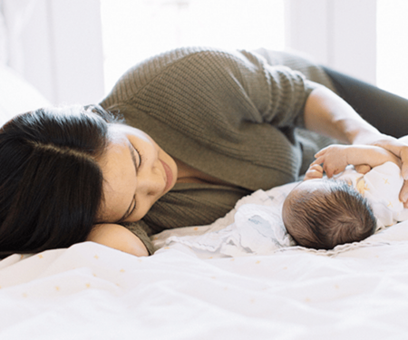 Newborn sleeping with mom on bed