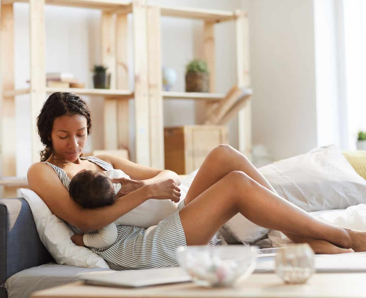 mother sitting on couch breastfeeding child